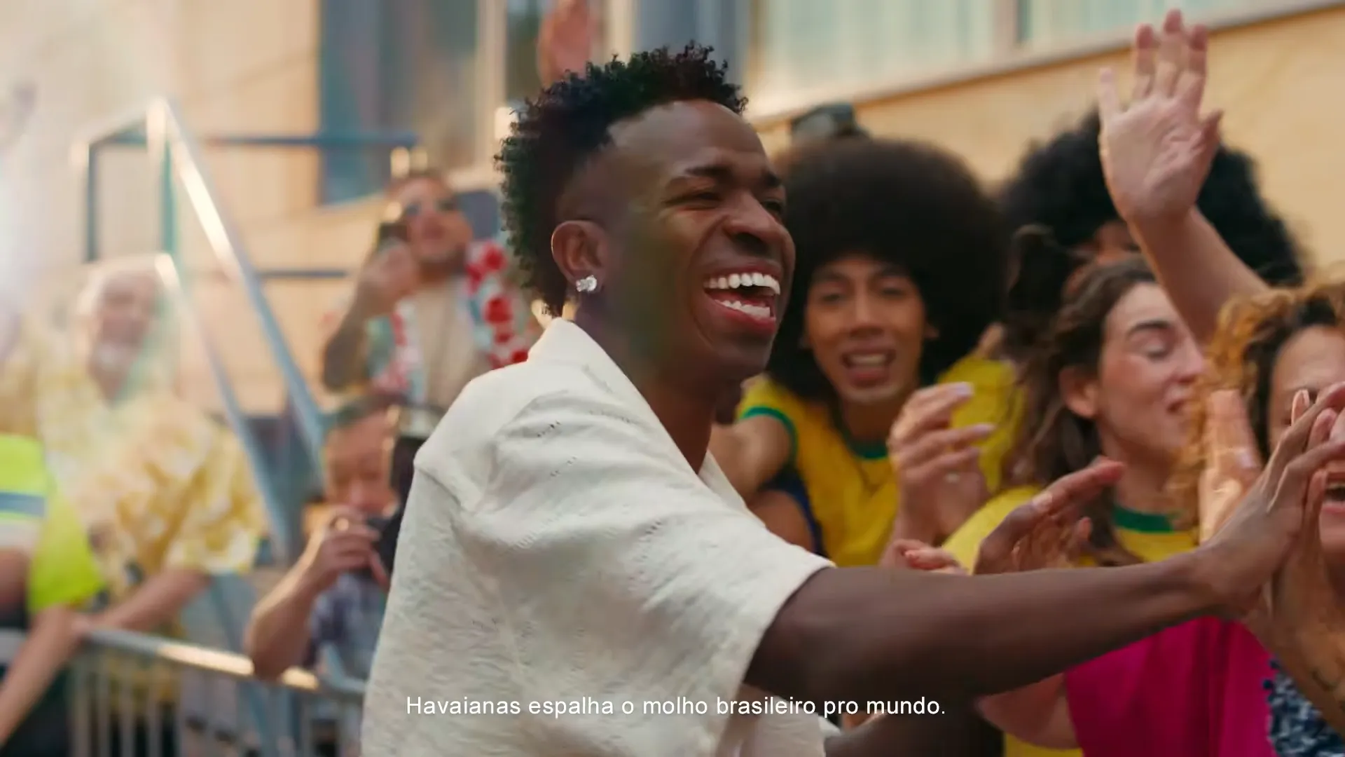 Homem sorrindo cumprimenta fãs em rua animada