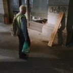 Homem caminhando na calçada com sacola e mochila