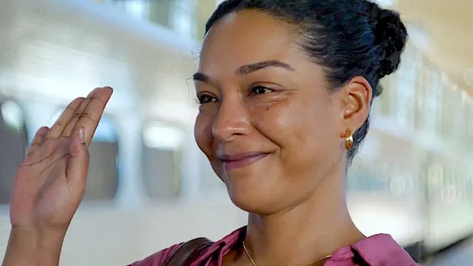 Mulher sorrindo acenando em estação de trem