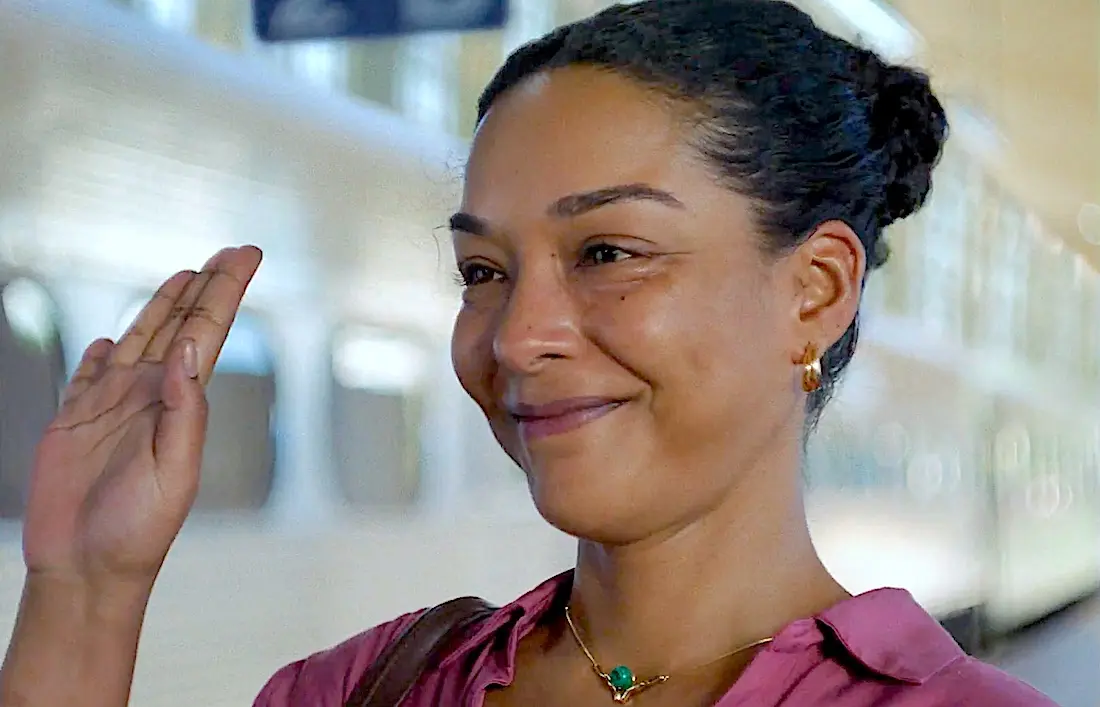 Mulher sorrindo acenando em estação de trem